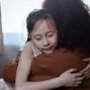 A parent and child sharing a warm, comforting hug
